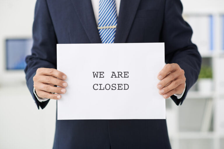 man holding sign that says we are closed showing his business is closed